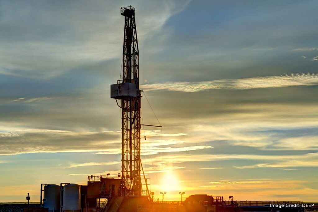 Geothermal drilling rig silhouetted against a sunset sky