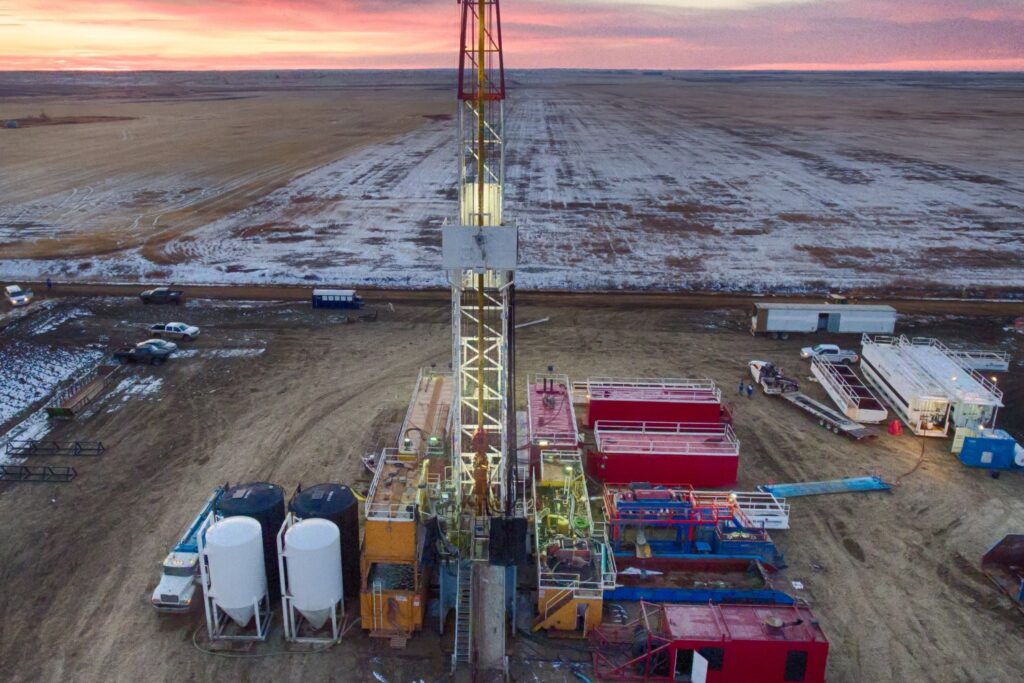 Aerial view of a drilling rig and equipment on a frosty site at dusk
